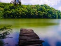 Wooden pier or jetty and a boat on lake sunset and sky reflection water. Royalty Free Stock Photo