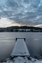 Wooden pier on lake with fresh snow.Winter pond with small jetty at sunrise,forest in backround.Frosty calm landscape. White