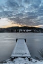 Wooden pier on lake with fresh snow.Winter pond with small jetty at sunrise,forest in backround.Frosty calm landscape. White