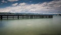 Wooden pier on lake Zurich with rolling hills mountain landscape and sailboats in the background Royalty Free Stock Photo