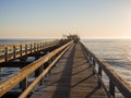 Wooden pier leading out into ocean with calm sea during soft sunset, Swakopmund, Namibia