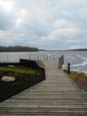 Wooden pier that leads to a viewing platform. Wooden site in front of the river. Wooden walkboard with a fence.