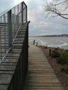 Wooden site in front of the river. Wooden walk board with a fence at cloudy day. Pier with balcony.