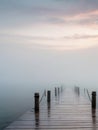 A wooden pier at misty dawn in a still sea Royalty Free Stock Photo