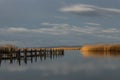 Wooden pier near the sea reflecting on it under the beautiful cloudy sky Royalty Free Stock Photo