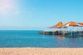 Wooden pier with orange-red awning over water of sea, lake, ocean with beach without people Royalty Free Stock Photo