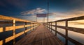 Wooden pier over the calm sea with the clouds in the sky in the background at sunrise Royalty Free Stock Photo