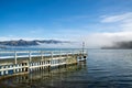Wooden pier and sailboat at Akaroa harbor, New Zealand. Clear sky with a few white clouds and mist. Symbol for relaxation, wealth