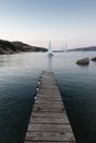 Wooden pier and sailboats sailing in evening calm sea of marvellous Porto Rafael, Costa Smeralda, Sardinia, Italy Royalty Free Stock Photo