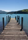 A wooden pier, sea and green hills in Akaroa near Christchurch in the South Island in New Zealand Royalty Free Stock Photo