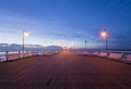 Wooden pier by the sea lit by stylish lamps at night Royalty Free Stock Photo