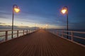 Wooden pier by the sea lit by stylish lamps at night Royalty Free Stock Photo