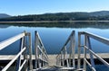 Wooden pier with stairs on a river with beach and forest. Water reflections, sunny day, blue sky. Galicia, Spain. Royalty Free Stock Photo