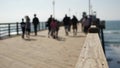 Wooden pier waterfront boardwalk, California beach USA. Defocused ocean, sea waves. People walking. Royalty Free Stock Photo