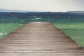 Wooden pier with waves on Lago di Garda Sirmione, Italy Royalty Free Stock Photo
