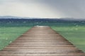 Wooden pier with waves on Lago di Garda Sirmione, Italy Royalty Free Stock Photo