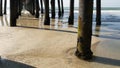 Wooden piles under pier in California USA. Pilings, pylons or pillars below bridge. Ocean waves tide