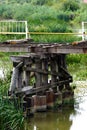 Wooden pillar supporting a broken bridge above a shallow water and vegetation. Royalty Free Stock Photo