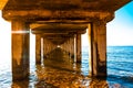 Wooden pillars underneath long old pier. Royalty Free Stock Photo