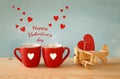 Wooden plane with heart next to couple of coffe cups