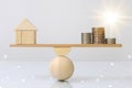 Wooden plank balancing of wood home and coins money comparison of income control expense with light effect graphic. Property inves