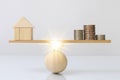 Wooden plank balancing of wood home and coins money comparison of income control expense with light effect graphic. Property inves