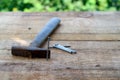 Wooden plank with a nail standing near a rusty hammer and a pile of nails in focus on a blurred nature background Royalty Free Stock Photo