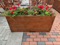 wooden planter box with red flowers and green plants on patio