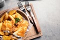 Wooden plate with British traditional fish and potato chips on table Royalty Free Stock Photo