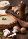 Wooden plate of creamy chestnut champignon mushroom soup with wooden spoon, pepper and kitchen cloth on wooden background Royalty Free Stock Photo