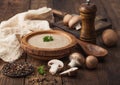 Wooden plate of creamy chestnut champignon mushroom soup with wooden spoon, pepper and kitchen cloth on wooden background Royalty Free Stock Photo