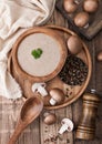 Wooden plate of creamy chestnut champignon mushroom soup with wooden spoon, pepper and kitchen cloth on wooden background Royalty Free Stock Photo