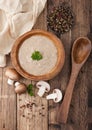 Wooden plate of creamy chestnut champignon mushroom soup with wooden spoon, pepper and kitchen cloth on wooden background. Top Royalty Free Stock Photo