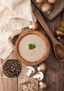 Wooden plate of creamy chestnut champignon mushroom soup with wooden spoon, pepper and kitchen cloth on wooden background. Top Royalty Free Stock Photo