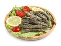 Wooden plate with delicious fried anchovies, lemon slices, tomatoes and lettuce leaves on white background