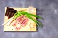 Wooden plate with a glass of cold Russian vodka, a piece of lard, green onions, garlic and slices of rye bread on a gray