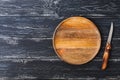 A wooden plate and knife with a wooden handle on a rustic black background. Royalty Free Stock Photo