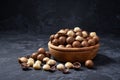 Shelled and unshelled macadamia nuts in wooden bowl on black background, close-up Royalty Free Stock Photo