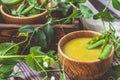 Wooden plate of pea soup and pods of fresh green peas on dark wooden surface Royalty Free Stock Photo