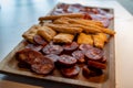 Wooden plate with sliced Spanish tapas, choriso sausage, lomo iberico en bread sticks Royalty Free Stock Photo