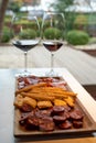 Wooden plate with sliced Spanish tapas, choriso sausage, lomo iberico en bread sticks served with glass of red wine