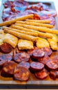 Wooden plate with sliced Spanish tapas, choriso sausage, lomo iberico en bread sticks Royalty Free Stock Photo