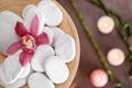 Wooden plate with spa stones and orchid flower on blurred background Royalty Free Stock Photo