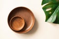 Wooden plates and monstera leaf flat lay composition. Empty dishes on light beige background, top view. Mockup for menu or recipe