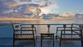 On a wooden platform above the ocean are a table and two chairs. The ocean is calm. Royalty Free Stock Photo