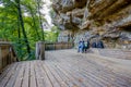 Wooden platform in a viewpoint, bench with two hikers taking a break with their brown dog