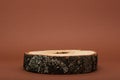 Wooden podium on brown background, sawn with bark, eco scene for presentation of beauty products