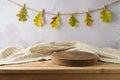 Wooden podium on table with modern tablecloth over autumn leaves garland background. Autumn kitchen mock up for design and product