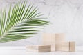 Wooden podiums with green palm leaf in sunlight on white wood table and marble wall. Fashion showcase for cosmetic products, goods Royalty Free Stock Photo