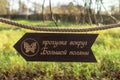 Wooden pointer in the form of an arrow on an old thick rope in the forest. Wonderful natural environment. Caption: Walk around a Royalty Free Stock Photo